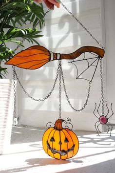 a hand holding a pumpkin with chains attached to it's face and hanging from the ceiling