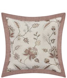 a white and brown pillow with flowers on the front, along with a tan border