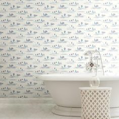 a bath tub sitting next to a wall with blue and white wallpaper on it