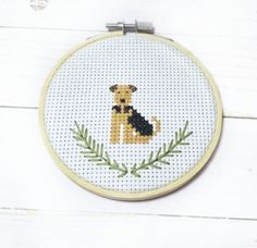 a cross stitch dog sitting on top of a wooden floor next to a white wall