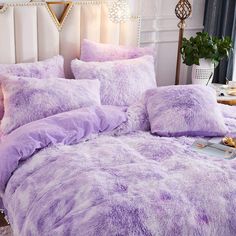 a bed covered in purple fluffy blankets and pillows