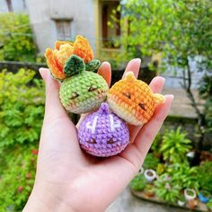 someone is holding two small crocheted toys in their hand, one with a pumpkin and the other with a cat on it