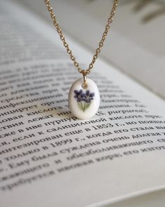 an open book with a necklace that has flowers on the front and back of it