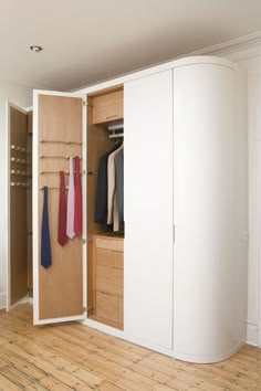 an open closet with ties hanging on the door and clothes in it, next to a wall mounted coat rack