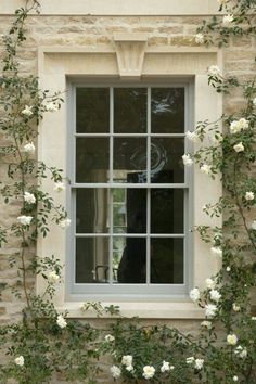 an open window with white roses growing around it