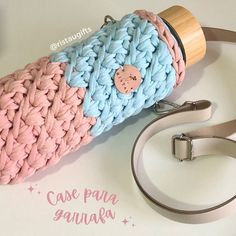 a pink and blue crochet bag with a wooden handle on a white table