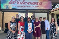 a group of people standing in front of a welcome sign