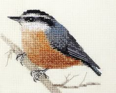 a cross stitch bird sitting on top of a tree branch in front of a white background