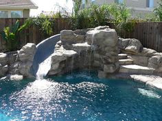 an outdoor pool with waterfall and rocks