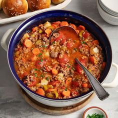 a blue bowl filled with meat and vegetables on top of a table next to other dishes