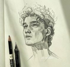 a pencil drawing of a man's face with curly hair on paper next to two markers