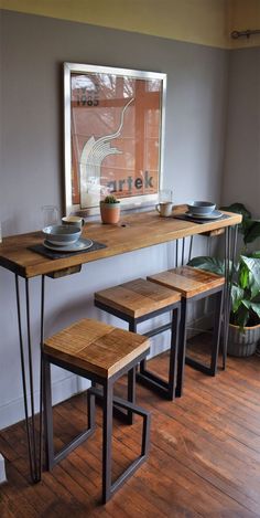 a wooden table with three stools next to it and a potted plant in the corner