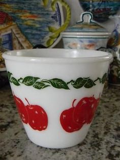 a white bowl with cherries on it sitting on a counter next to other dishes