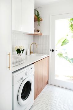 a washer and dryer in a small room with white tile flooring on the walls