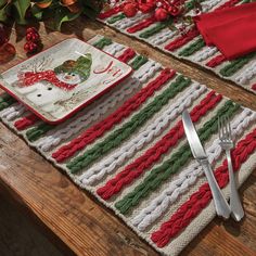 the table is set with red and green placemats, silverware, and christmas decorations