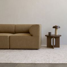 a brown couch sitting next to a table on top of a white carpeted floor