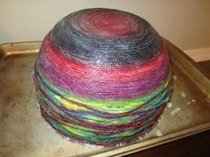 a roll of yarn sitting on top of a metal pan covered in multicolored yarn