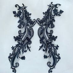 two black lace appliques on a white background, each with an intricate design