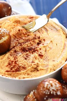 a white bowl filled with dip next to rolls