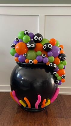 a black vase filled with lots of colorful balls and googly eyes on top of it