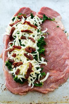 raw meat with parmesan cheese and other toppings on the top, sitting on a baking sheet