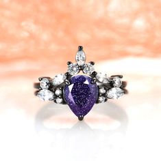 a ring with a purple heart surrounded by white and clear stones on an orange background