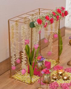 an arrangement of flowers and decorations on the floor in front of a gold stand with candles