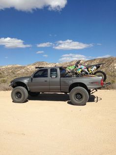 a pick up truck parked in the desert with a bike on the back of it