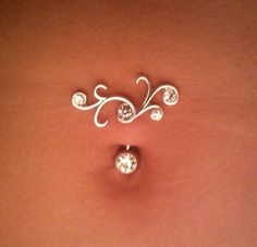 a woman's stomach with two piercings on it, one is white and the other is silver