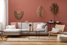 a living room with pink walls and white furniture in the corner, including a sectional sofa