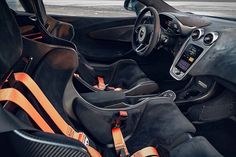 the interior of a sports car with black leather and orange trims, including steering wheel