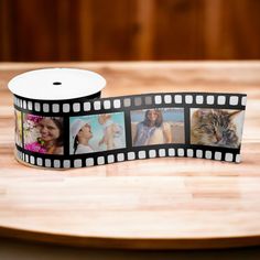 a roll of film sitting on top of a wooden table next to a cup filled with pictures