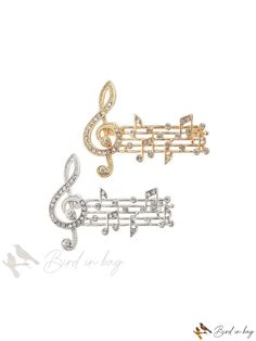 two brooches with musical notes and treble on them, one is gold and the other is silver