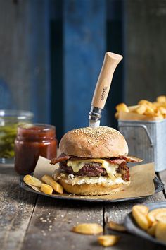 a cheeseburger with fries on the side and a knife sticking out of it