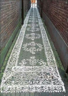 an alley way with brick walls and white designs on the floor