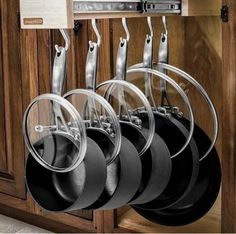 pots and pans are hanging on the rack in front of a cabinet with wooden doors