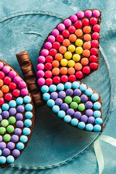 two heart shaped cookies decorated with candy on a plate