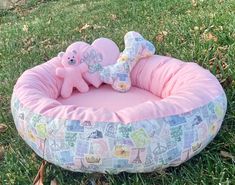 a pink dog bed in the grass with two stuffed animals