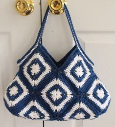 a blue and white crocheted purse hanging from a hook on a door handle