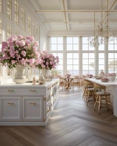 a large kitchen with white cabinets and pink flowers in vases on the counter top