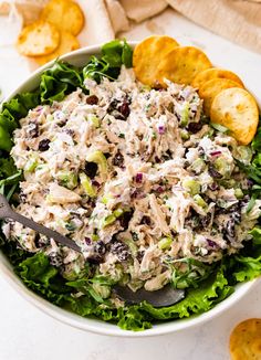 a white bowl filled with chicken salad next to crackers and chips on the side