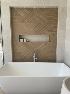 a large white bathtub sitting next to a window in a room with wood paneling on the walls