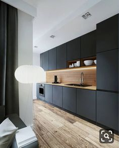 a modern kitchen with black cabinets and wood flooring is pictured in this image from the side view