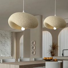 two circular lights hanging from the ceiling above a dining room table with chairs and stools