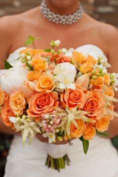 a bride holding a bouquet of orange and white flowers