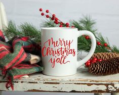 a coffee mug sitting on top of a table next to pine cones and christmas decorations