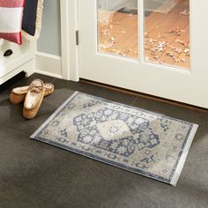 a pair of slippers sitting on the floor in front of a door with a rug