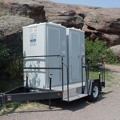 two portable toilets sitting on the side of a road next to some grass and rocks