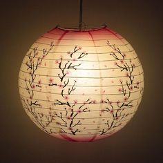 a paper lantern with branches on it hanging from a ceiling fixture in a dark room