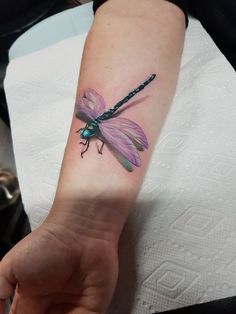 a woman's arm with a dragonfly tattoo on it